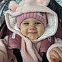 baby, infant, child, smile, pink_clothing, beanie, hood, fuzzy_coat, car_seat, harness, stroller, blue_eyes, cheeks, portrait, close_up, winter_clothing, cute, button, hand, cozy