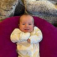 Rowan joined the competition — help win amazing prizes! baby, smiling, onesie, purple_cushion, couch, pillows, indoor, face, child, happy, infant, cozy, homedecor, comfort, person, cute, relaxing, small_child, seated, soft_furniture