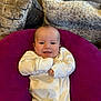 baby, smiling, onesie, purple_cushion, couch, pillows, indoor, face, child, happy, infant, cozy, homedecor, comfort, person, cute, relaxing, small_child, seated, soft_furniture