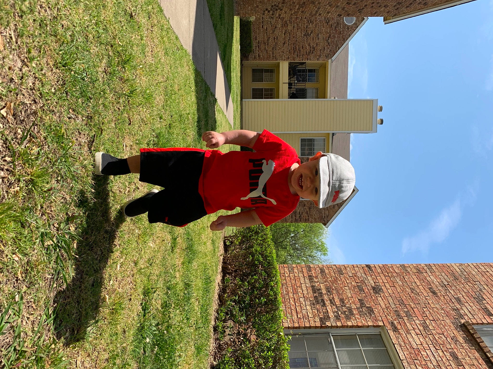 Graeson is registered to the contest to win money with this photo: building, facade, fun, grass, headwear, house, leisure, line, person, plant, shadow, shrub, sky, tree, walking_shoe, window, world