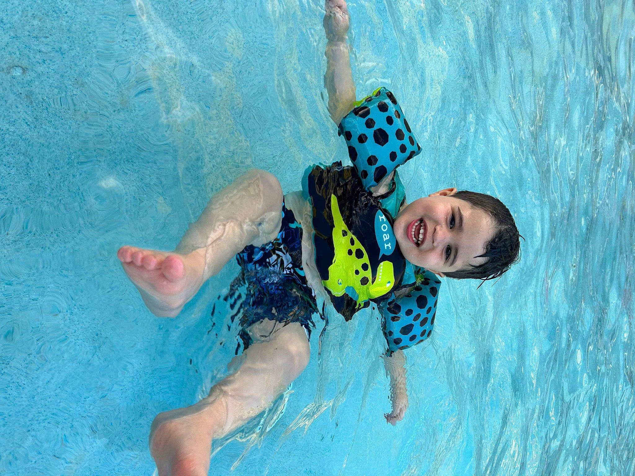 Jeremiah is registered to the contest to win money with this photo: aqua, azure, child, electric_blue, fun, happy, joy, leisure, outdoor_recreation, person, personal_protective_equipment, recreation, smile, sports, swimmer, swimming_pool, swimwear, thigh, toddler, vertebrate