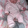 baby, infant, pink_clothing, hooded_outfit, baby_seat, patterned_cushion, indoor, portrait, child, cute, baby_girl, face, seated, clothing, looking, expression, small_hands, soft_texture, cozy, adorable
