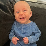 Jackson is registered to the contest to win money with this photo: baby, smiling, blue_outfit, couch, happy, infant, child, indoor, person, cute, portrait, young, sitting, hands, face, skin, head, eyes, cozy, comfort