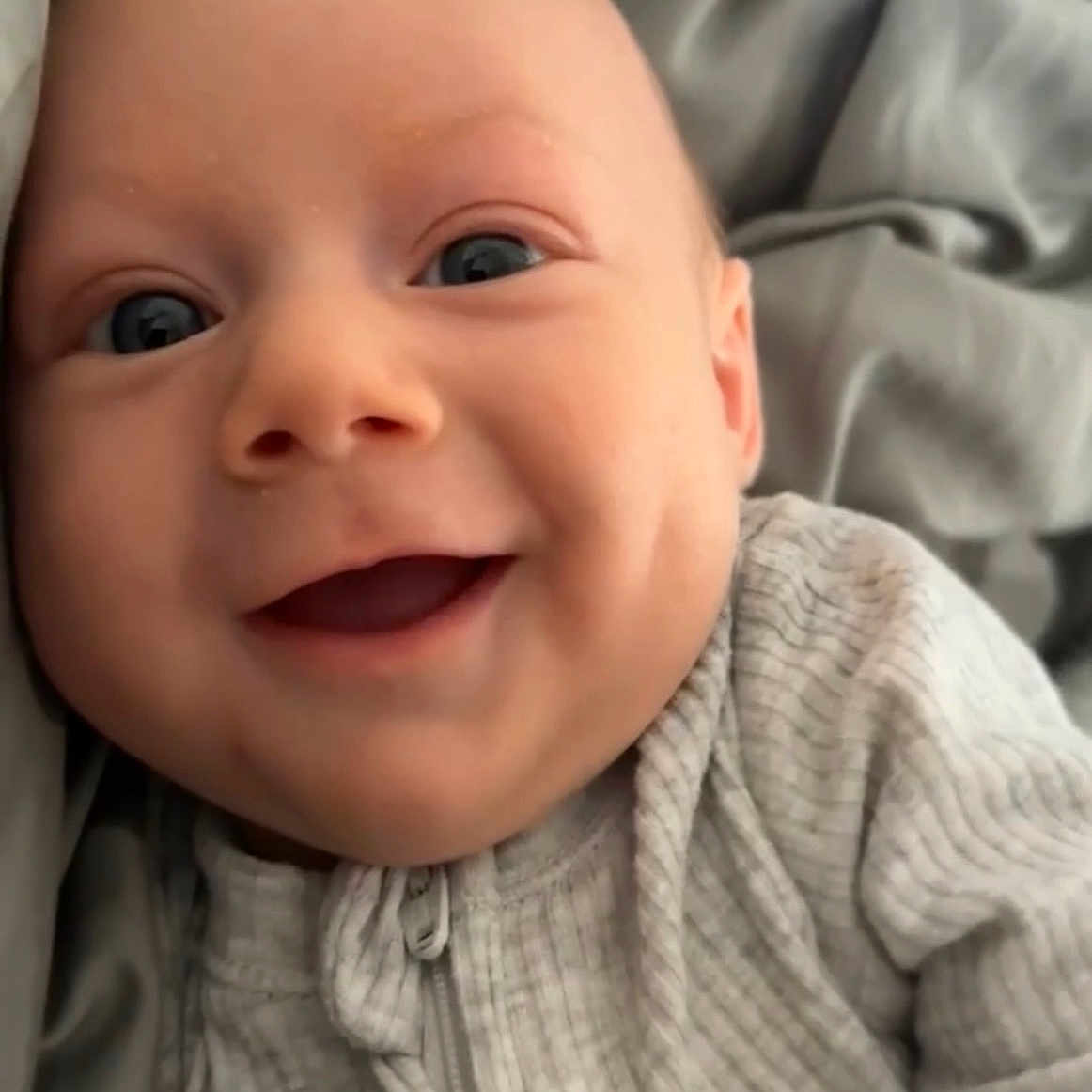 Jackson joined the competition — help win amazing prizes! baby, bed, blanket, closeup, clothing, cozy, cute, eyes, face, happy, indoors, infant, person, portrait, ribbed_fabric, skin, smiling, soft_texture, young_child, zipper