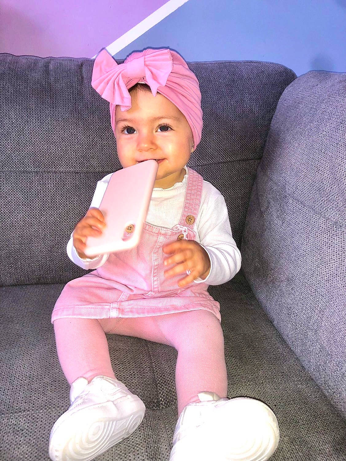 Loélia participe au concours pour gagner de l'argent avec cette photo : baby, baby_toddler_clothing, cap, comfort, couch, face, finger, headwear, lap, leg, linens, magenta, person, pink, sitting, skin, sleeve, sneakers, sock, textile