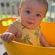 Hudson joined the competition — help win amazing prizes! baby, child, yellow_bucket, tank_top, palm_tree_print, curious, portrait, indoors, hand, face, skin, cute, expression, short_hair, summer_clothing, natural_light, background_blur, person, infant, closeup