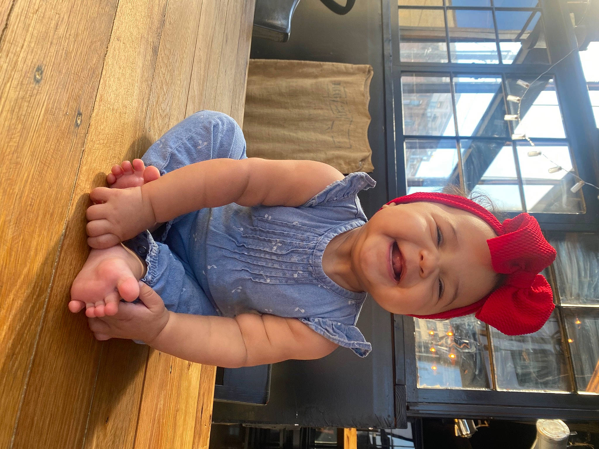 Addilynn is registered to the contest to win money with this photo: arm, barefoot, child, comfort, elbow, foot, fun, hardwood, hat, human_leg, jeans, joint, knee, leisure, person, sitting, smile, t_shirt, thigh, toddler