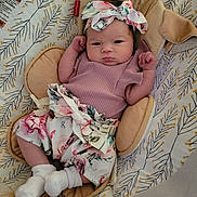 Lily joined the competition — help win amazing prizes! baby, infant, child, headband, floral, pattern, cushion, seat, clothing, socks, cute, portrait, indoors, comfortable, soft, newborn, face, hands, lying, resting