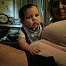 Wilson is registered to the contest to win money with this photo: adult, baby, bib, caregiver, child, clock, curious, eyes, face, family, framed_picture, home, indoor, infant, lap, photograph, portrait, shirt, sitting, toys