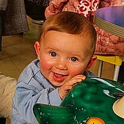 Maël participe au concours pour gagner de l'argent avec cette photo : baby, child, smiling, indoor, playful, green, ceramic, animal, hand, clothing, person, face, happy, table, jacket, background, people, coat, toy, support