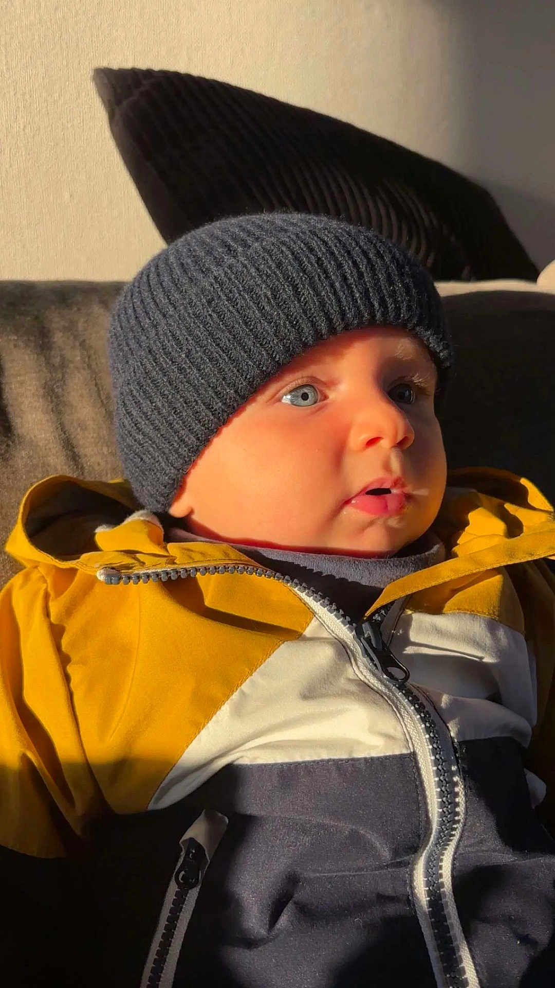 Maël a rejoint le concours — aidez-le/la à gagner de superbes lots ! baby, child, hat, knit_hat, jacket, zipper, blue_eyes, face, portrait, indoors, light, shadow, warm_clothing, curious, cute, toddler, person, closeup, cozy, soft_light
