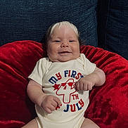 Thiago joined the competition — help win amazing prizes! baby, infant, smile, red_cushion, blue_sofa, onesie, clothing, sitting, happy, face, skin, arm, hand, leg, indoor, celebration, holiday, cute, child, portrait
