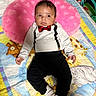 Samuel is registered to the contest to win money with this photo: baby, infant, toddler, clothing, tuxedo_outfit, pink_pillow, quilt, animal_prints, giraffe, elephant, yellow, blue, white, black_pants, socks, bed, cute, indoors, portrait, child