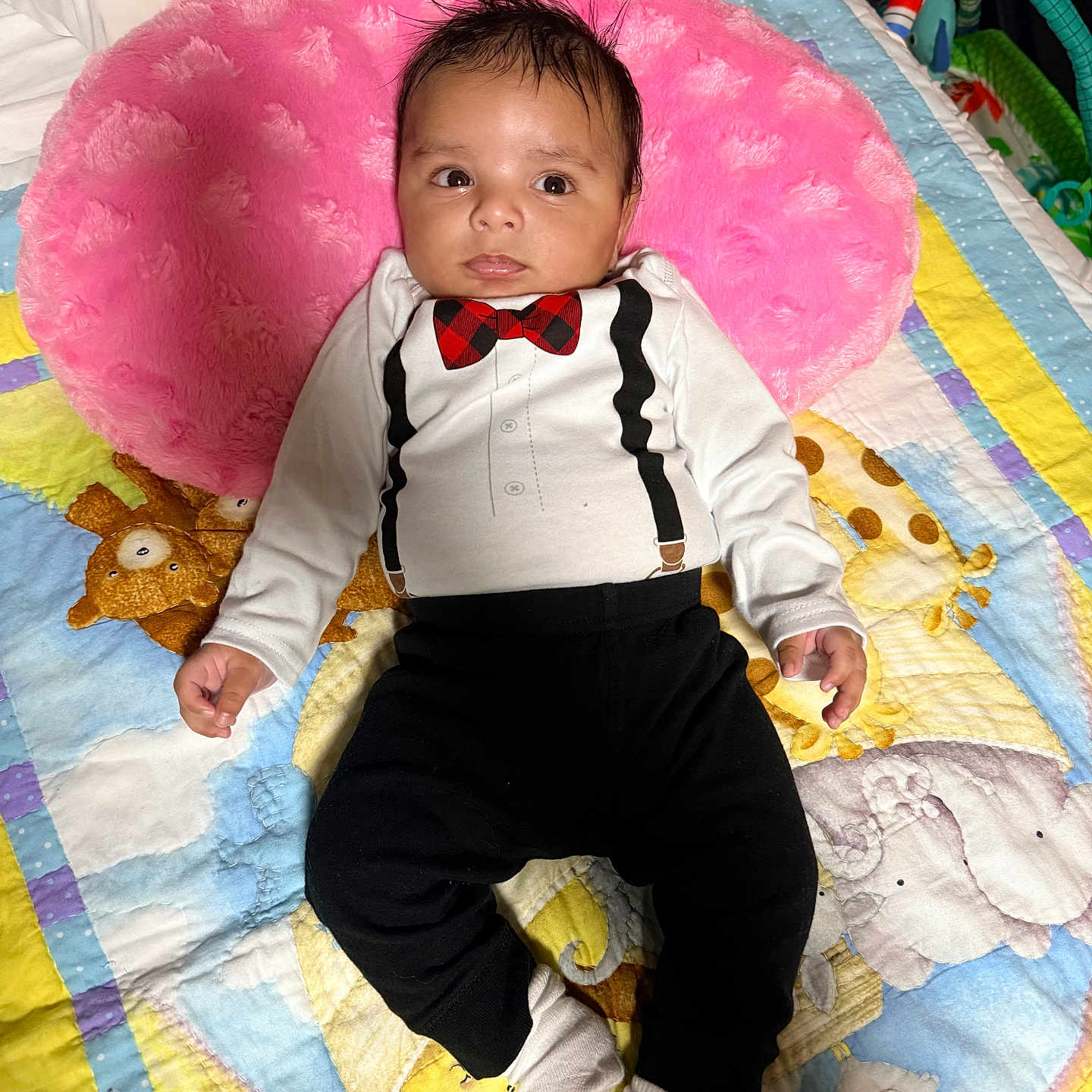 Samuel is registered to the contest to win money with this photo: baby, infant, toddler, clothing, tuxedo_outfit, pink_pillow, quilt, animal_prints, giraffe, elephant, yellow, blue, white, black_pants, socks, bed, cute, indoors, portrait, child
