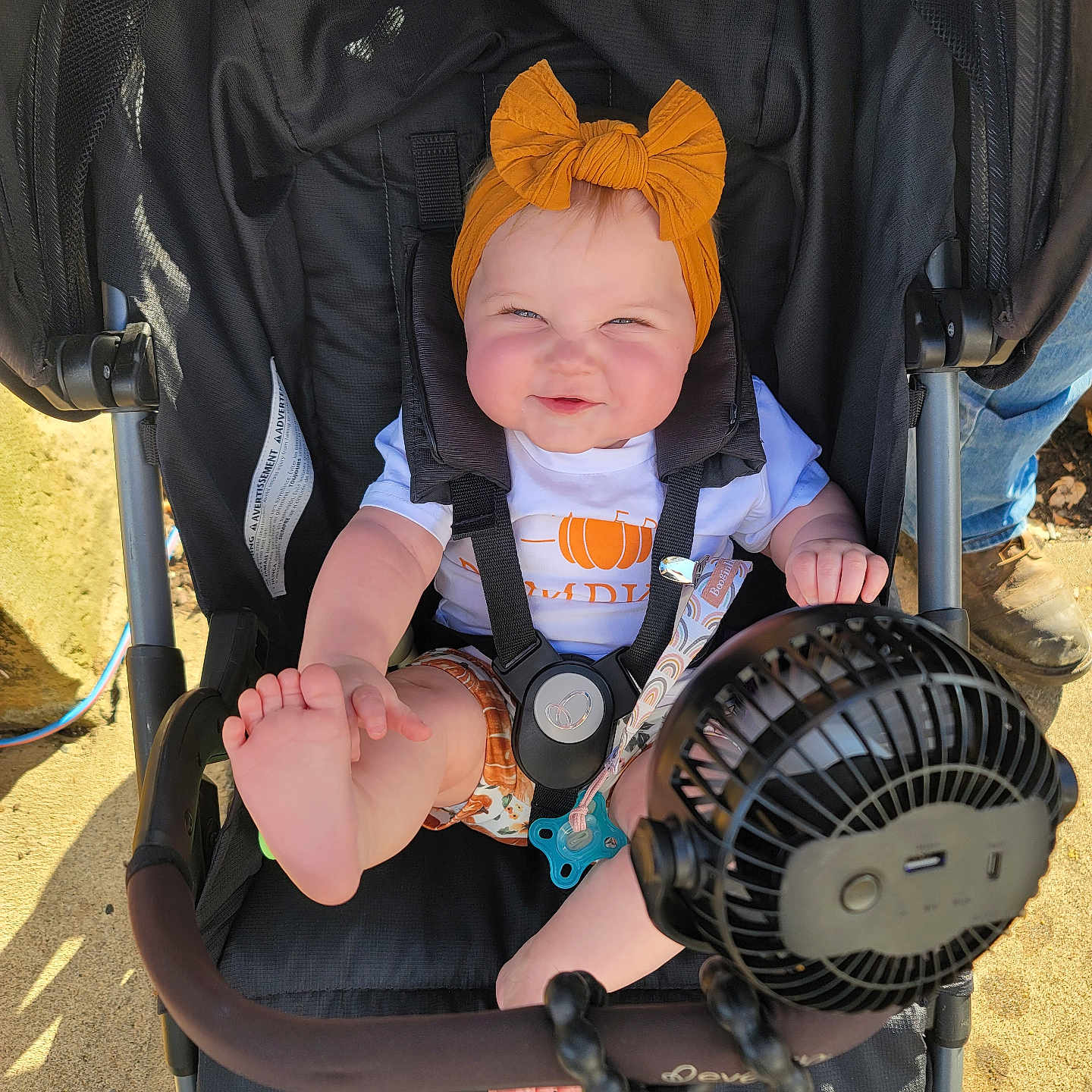Letty is registered to the contest to win money with this photo: accessory, baby, black, child, clothing, cute, fan, foot, happy, headband, infant, orange, outdoor, person, playful, seatbelt, smiling, stroller, summer, sunlight