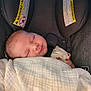 baby, sleeping, blanket, car_seat, child, infant, face, head, clothing, warning_label, seatbelt, soft_texture, rest, peaceful, closeup, portrait, indoors, comfort, newborn, cute