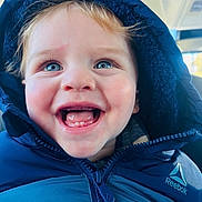 Shane is registered to the contest to win money with this photo: child, toddler, smile, teeth, blue_hood, puffer_jacket, reebok_logo, hood, zipper, face, eyes, rosy_cheeks, car_interior, closeup, happy, portrait, winter_clothing, infant, young_child, joyful