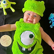 Kaël a rejoint le concours — aidez-le/la à gagner de superbes lots ! baby, child, costume, halloween, green, plush_toy, smile, face, hat, monster, cute, happy, infant, black_background, soft_texture, teeth, eye, celebration, holiday, lying_down