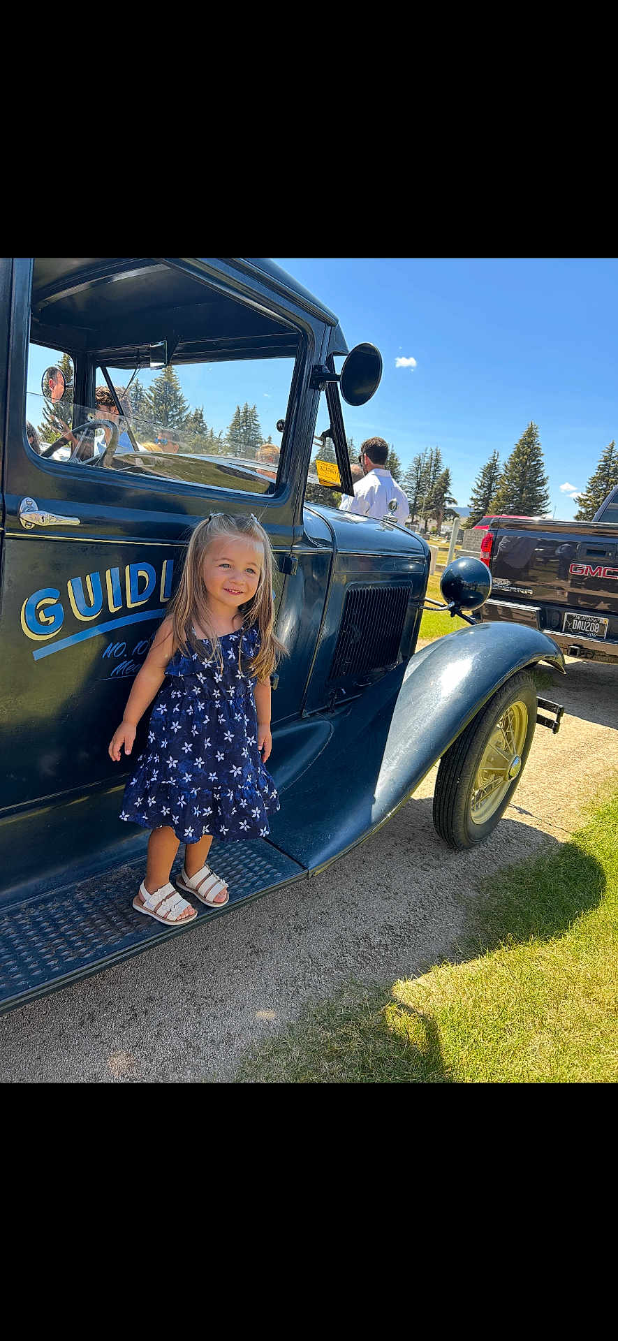 Kaylynn joined the competition — help win amazing prizes! child, girl, vintage_truck, blue_dress, sandals, outdoor, sunny, grass, trees, sky, vehicle, smile, standing, daylight, classic_car, nature, people, park, reflection, side_view