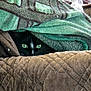 cat, black_cat, green_eyes, blanket, quilt, cozy, hiding, indoor, pet, fur, texture, pattern, feline, resting, curious, warm, comfort, soft, hidden, animal
