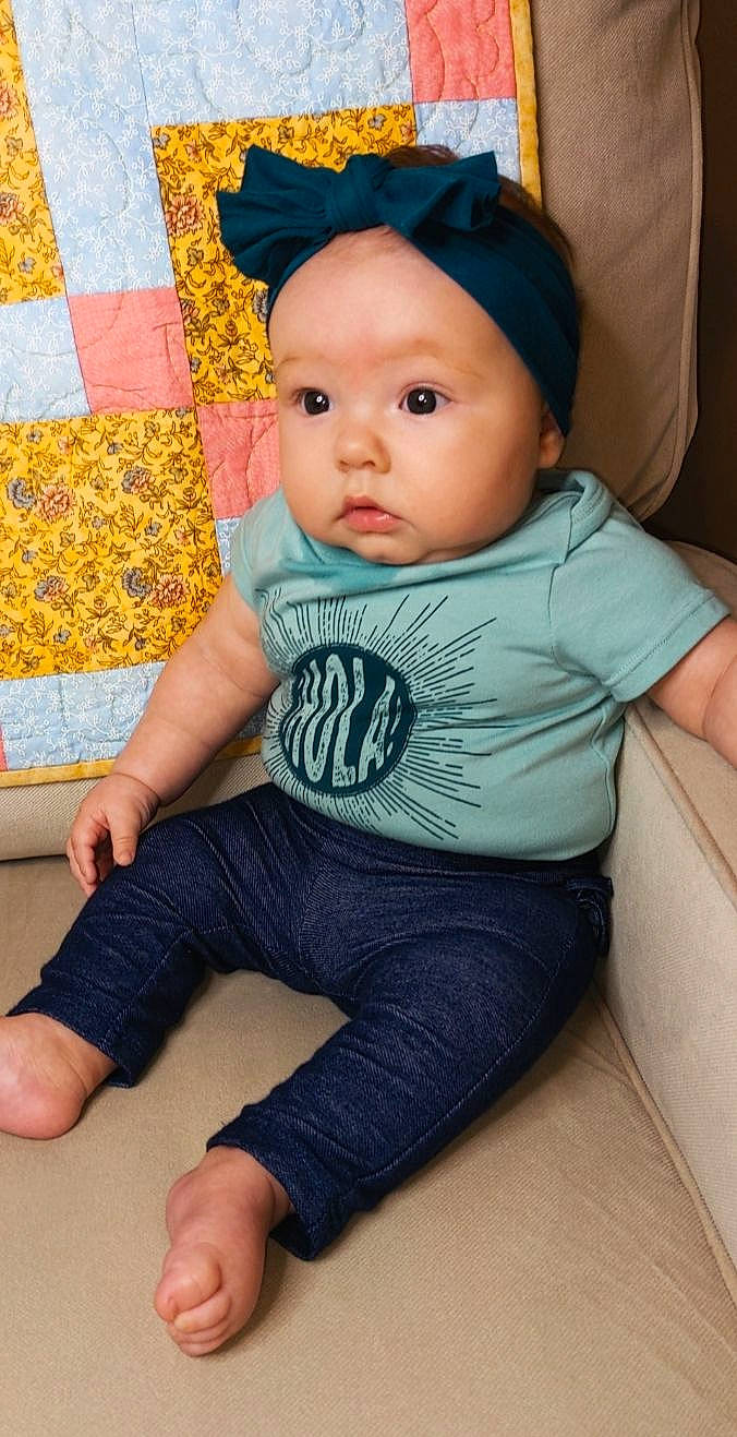 Gabrielle is registered to the contest to win money with this photo: baby, baby_toddler_clothing, blue, cap, cheek, child, chin, comfort, finger, flooring, headwear, knee, leg, pattern, person, photograph, sitting, skin, sleeve, t_shirt