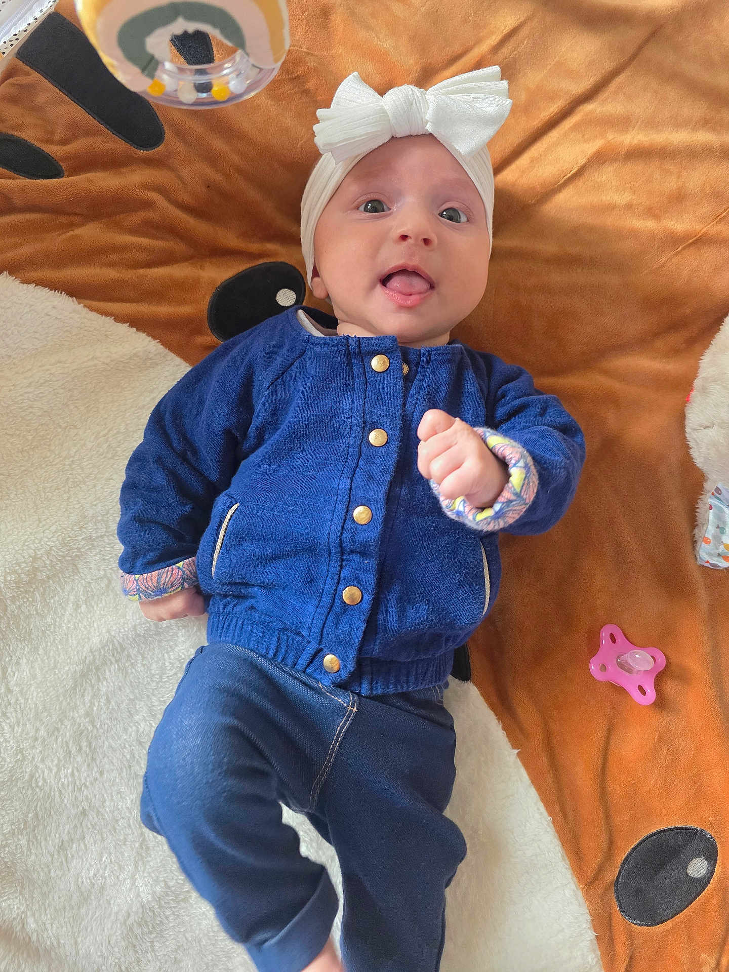 Rose a rejoint le concours — aidez-le/la à gagner de superbes lots ! baby, infant, headband, blue_jacket, blanket, pacifier, toy, playtime, cute, lying_down, indoors, child, face, expression, clothing, hand, footwear, fabric, comfort, smile