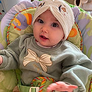 Leylana participe au concours pour gagner de l'argent avec cette photo : baby, child, infant, knitted_hat, baby_seat, child_seat, strapped_in, curious_expression, wide_eyes, hand, clothing, sweater, indoor, soft_tones, animal_pattern, cute, portrait, close_up, seat_belt, adorable