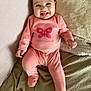 baby, blanket, butterfly_design, child, cozy, cute, face, feet, happy, head, indoors, infant, lying_down, person, pink_onesie, small_hands, smiling, soft_texture, tongue_out, warm_clothing