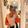 Lilyana a rejoint le concours — aidez-le/la à gagner de superbes lots ! woman, baby, mirror, selfie, baby_carrier, orange_shirt, black_pants, home_interior, wall_decor, bracelet, phone_case, sleeping_baby, baby_wrap, indoor, portrait, person, reflection, casual_clothing, hair_bun, cozy