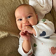 Lilyana participe au concours pour gagner de l'argent avec cette photo : baby, infant, smiling, hand, face, eyes, clothing, blanket, onesie, heart_pattern, fingers, lying_down, cute, soft_texture, warm_colors, happy, indoors, child, skin, portrait