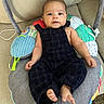 Thiago joined the competition — help win amazing prizes! baby, child, infant, overalls, plaid, baby_seat, cushion, colorful, indoor, carpet, sofa, curly_hair, barefoot, face, smiling, person, young_child, comfort, relaxing, portrait