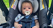 Thiago joined the competition — help win amazing prizes! baby, pacifier, car_seat, blue_clothing, knitwear, infant, child, outdoor, greenery, curious, sitting, straps, safety_harness, face, head, white_socks, cute, portrait, young_child, daylight