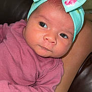 Sol is registered to the contest to win money with this photo: baby, infant, headband, bow, pink_clothing, person, face, eyes, indoor, couch, legs, skin, portrait, closeup, cute, newborn, child, seated, cozy, colorful