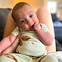 baby, infant, child, pajamas, hand, legs, person, indoor, blurred_background, cute, sitting, looking_at_camera, face, skin, blue_eyes, comfort, soft_lighting, closeup, portrait, cozy
