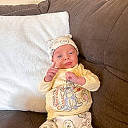 Kamden is registered to the contest to win money with this photo: baby, infant, pajamas, hat, couch, pillow, brown_couch, winnie_the_pooh, cartoon_characters, cute, child, indoor, smiling, clothing, soft_fabric, relaxed, small_hands, portrait, seated, home