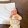 baby, infant, pajamas, hat, couch, pillow, brown_couch, winnie_the_pooh, cartoon_characters, cute, child, indoor, smiling, clothing, soft_fabric, relaxed, small_hands, portrait, seated, home