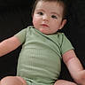 Liam joined the competition — help win amazing prizes! baby, infant, child, green_onesie, socks, chubby_legs, lying_down, indoor, cute, young_child, face, skin, short_hair, person, apparel, fabric, blur, motion, relaxing, soft_surface