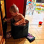 baby, ball, book, child, colorful, curious, daylight, floor, furniture, home, indoor, person, playing, playroom, small_car, storage_bin, tiles, toddler, toy, window