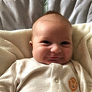 Finley is registered to the contest to win money with this photo: baby, smiling, blanket, onesie, lion_patch, infant, cute, face, portrait, child, soft, cozy, happy, indoors, newborn, clothing, head, skin, expression, resting
