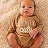 baby, infant, onesie, brown_clothing, text_on_clothing, fluffy_blanket, soft_texture, cute, portrait, sitting, barefoot, skin, face, eyes, hands, feet, newborn, cozy, indoor, child