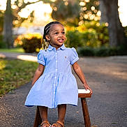 Jream is registered to the contest to win money with this photo: child, clothing, dress, face, female, footwear, formalwear, girl, happy, head, pants, person, photography, portrait, sandal, shoe, sitting, sleeve, smile, wood