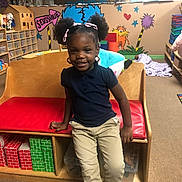 Joahni joined the competition — help win amazing prizes! bench, casual_clothing, child, classroom, decorations, educational, flooring, girl, hair_ribbons, happy, indoor, person, pigtails, playroom, red_cushion, seussville, smiling, toys, wooden_furniture, young_child