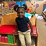 bench, casual_clothing, child, classroom, decorations, educational, flooring, girl, hair_ribbons, happy, indoor, person, pigtails, playroom, red_cushion, seussville, smiling, toys, wooden_furniture, young_child