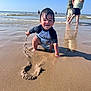 toddler, child, beach, sand, water, ocean, waves, wet_hair, swim_shirt, disney, playing, happy, squatting, sunny, blue_sky, reflection, people, walking, summer, outdoor