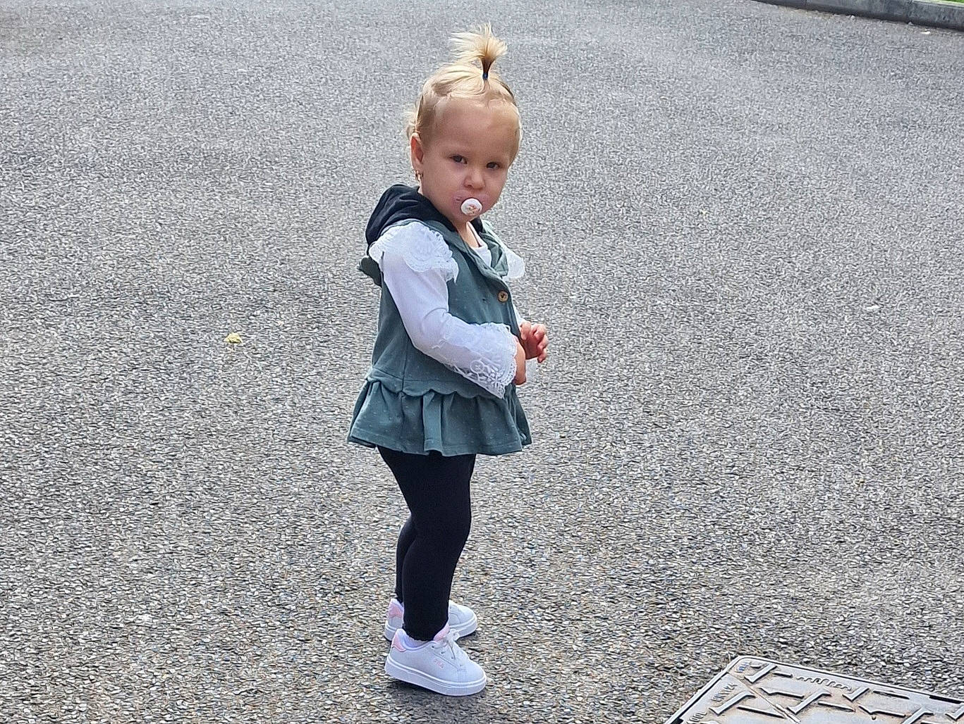 Evelin is registered to the contest to win money with this photo: asphalt, city, denim, flooring, gesture, grass, happy, human_leg, leisure, pedestrian, people_in_nature, person, public_space, road, road_surface, shadow, sidewalk, standing, street, toddler