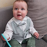 Arthur participe au concours pour gagner de l'argent avec cette photo : baby, child, toddler, couch, sofa, clothing, vest, bow_tie, green_pants, socks, brush, indoor, cute, smiling, happy, person, home, seated, face, expression