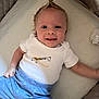 baby, baby_boy, baby_clothes, blue_pants, child, cute, cute_hairstyle, face, giraffe_print, happy, indoors, infant, lying_down, mohawk, numbers, person, portrait, smiling, soft_surface, white_shirt