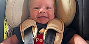 Arthur participe au concours pour gagner de l'argent avec cette photo : baby, car_seat, child, smile, infant, seatbelt, clothing, safety, cute, happy, straps, face, headrest, young_child, indoor, person, seat, toddler, hands, hair