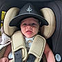 baby, infant, car_seat, hat, cap, face, tongue_out, straps, clothing, child, seatbelt, safety, cute, smiling, person, indoor, young, headwear, baby_boy, expression