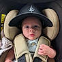 baby, infant, car_seat, hat, cap, straps, seatbelt, wide_eyes, expression, child, cute, indoor, clothing, hand, face, person, closeup, seat, safety, newborn
